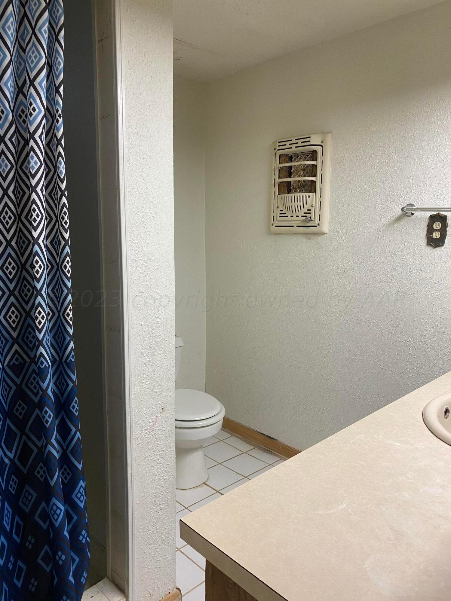 310 Santa Fe Street Borger, TX 79007 - Photo 14 of 18 a white toilet sitting next to a shower curtain