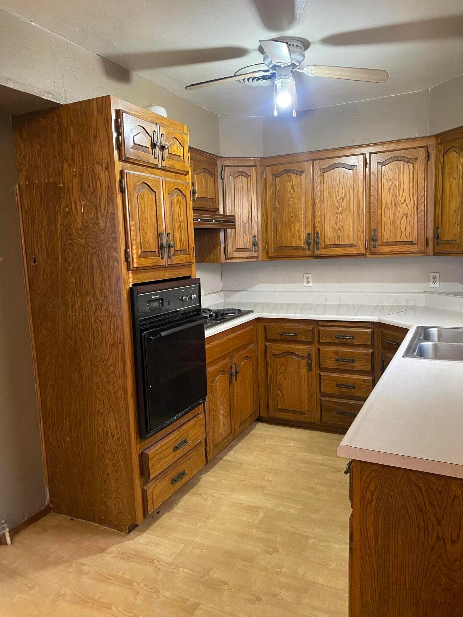 310 Santa Fe Street Borger, TX 79007 - Photo 5 of 18 a kitchen with granite countertop a refrigerator a sink dishwasher and wooden cabinets