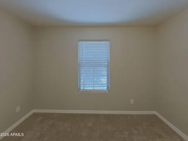a view of an empty room with closet and a window