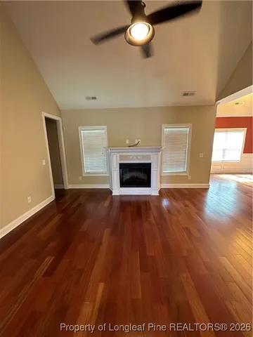 an empty room with wooden floor fireplace and windows