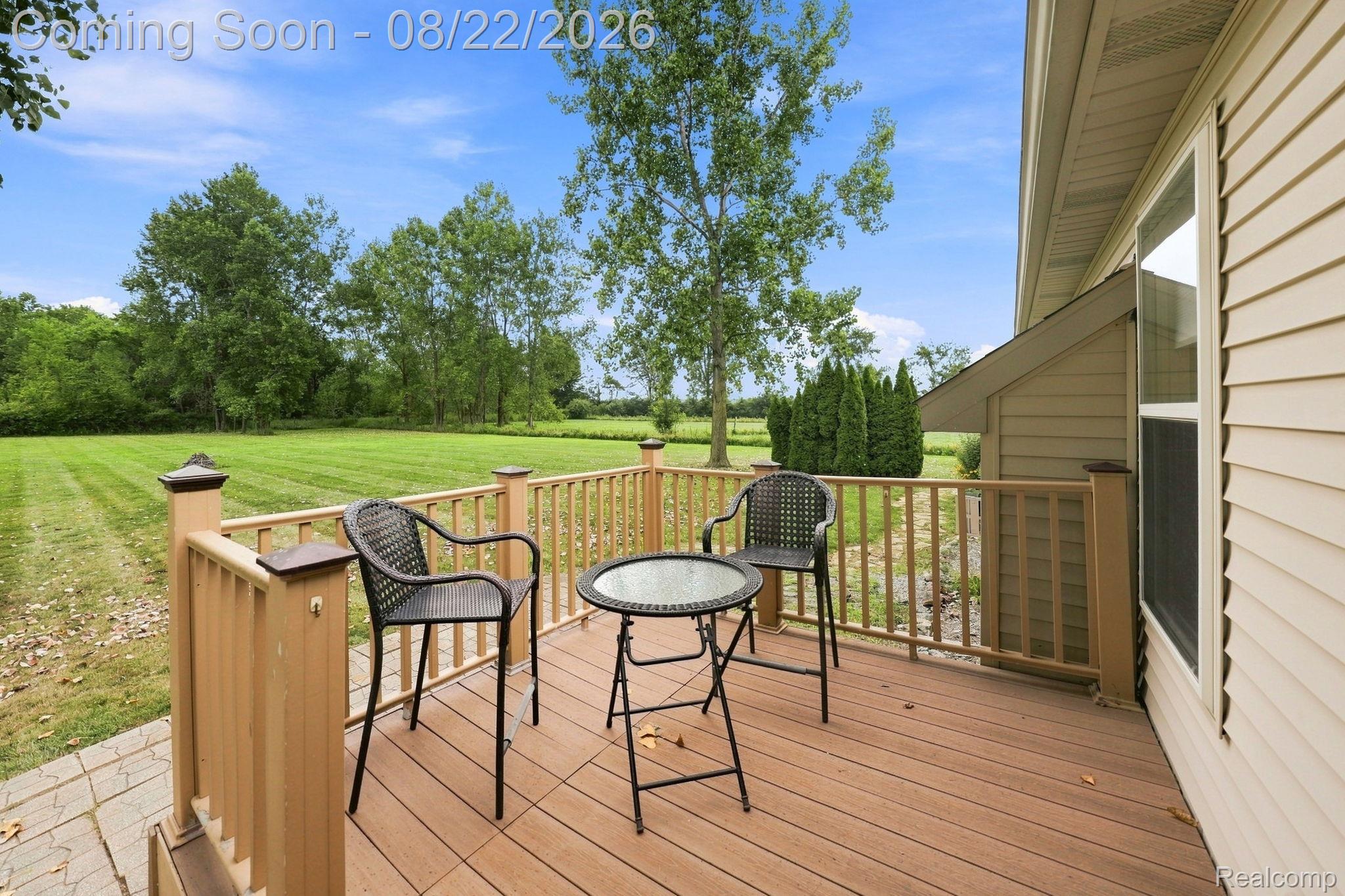 1301 Palms Road Columbus, MI 48063 - Photo 45 of 51 Exterior deck featuring wood-finish railings and flooring, expansive green lawn, and mature trees