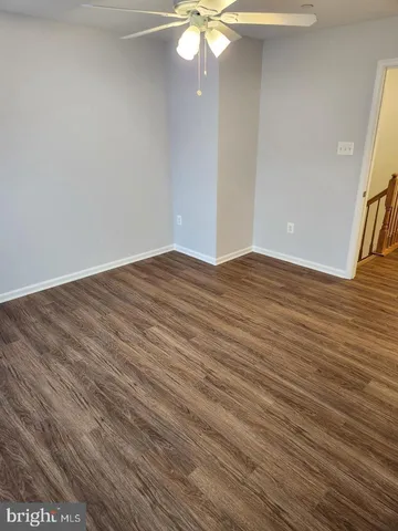 a view of a hallway with wooden floor and a bathroom