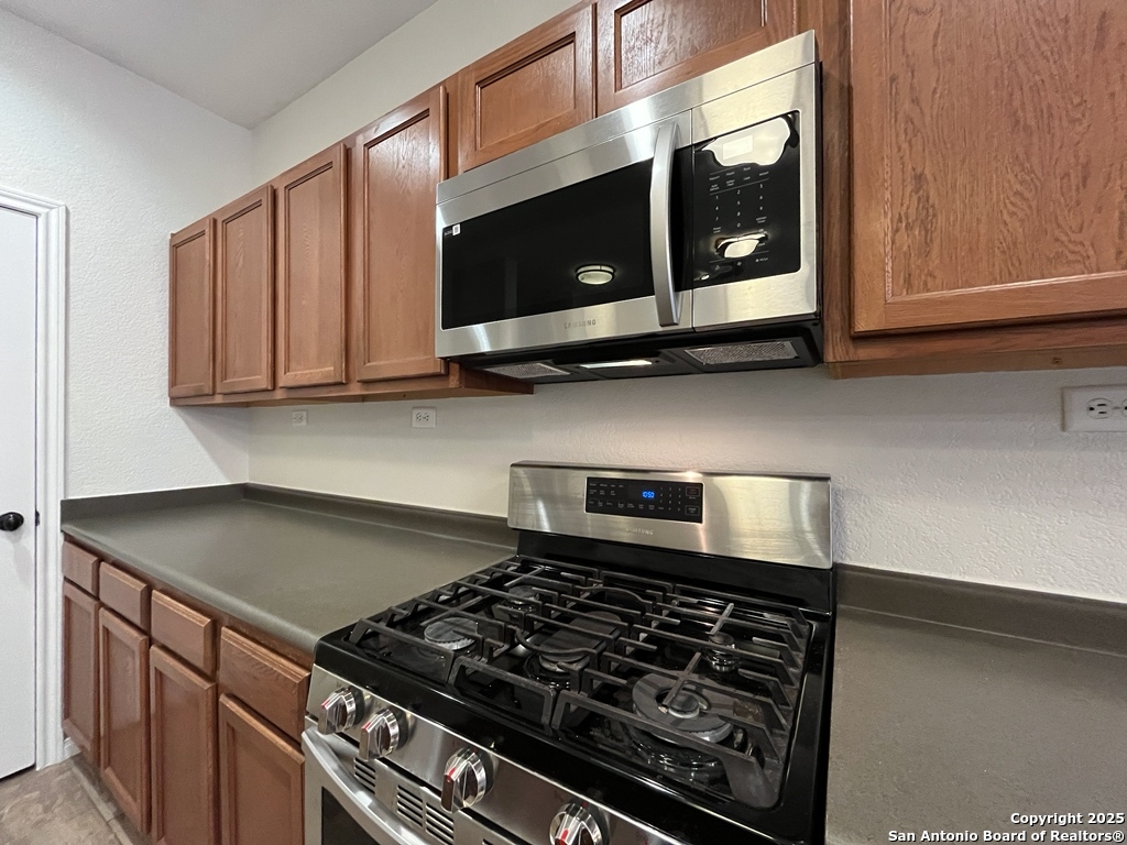 317 Sandy Shoal Boerne, TX 78006 - Photo 13 of 50 a kitchen with wooden cabinets and a stove top oven
