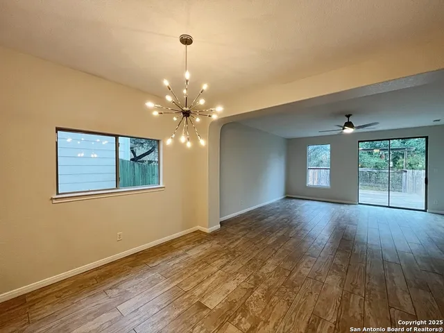 a view of an empty room with window and wooden floor