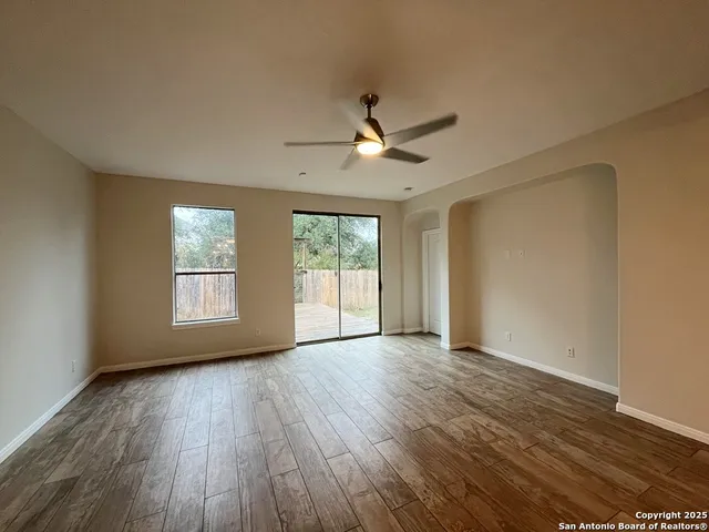 a view of an empty room with wooden floor and a window