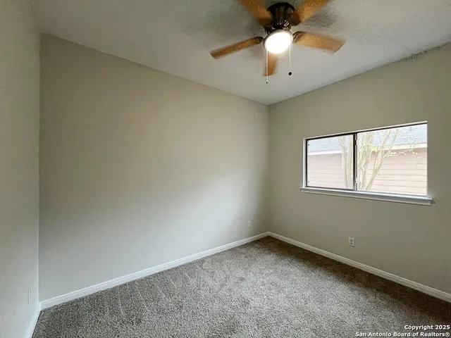 an empty room with a ceiling fan and a window