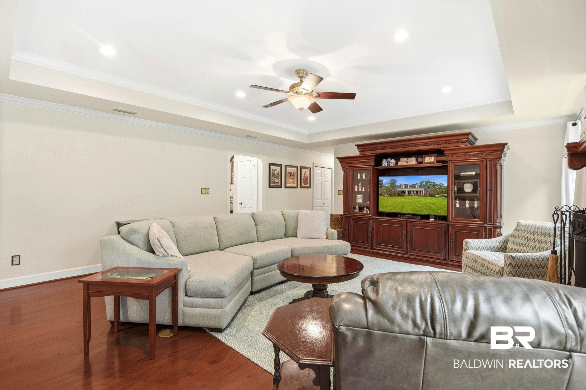 31515 Rhett Drive Spanish Fort, AL 36527 - Photo 25 of 100 The Great Room measures 21' 7' x 17' 7' and has beautiful engineered hardwood floors, crown molding, tray ceilings, two Andersen sliding doors (2024) with lead glass decorative transom to the patio and pool area, and a woodburning fireplace.