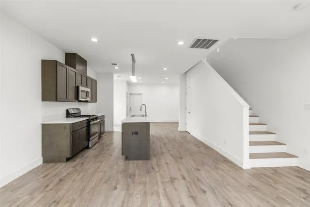 a large kitchen with a center island wooden floor and stainless steel appliances