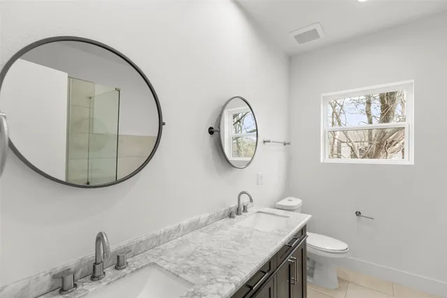 a bathroom with a granite countertop toilet a sink and a mirror
