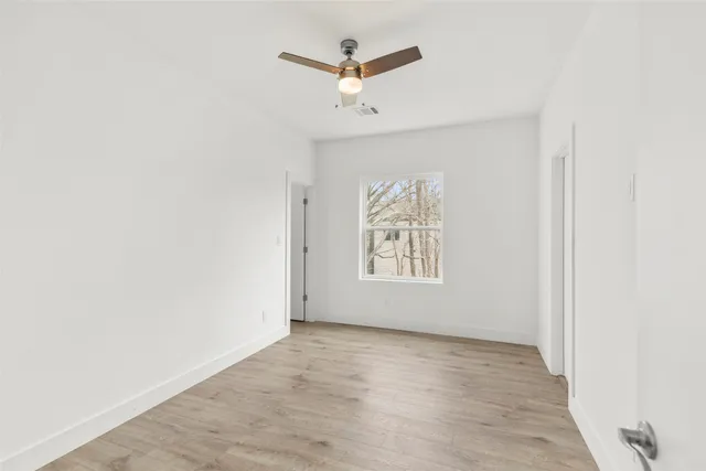 an empty room with window and ceiling fan