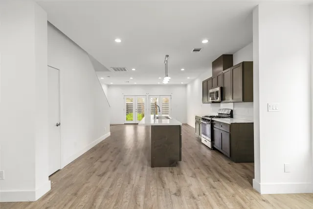 a large kitchen with stainless steel appliances kitchen island a large counter top and a wooden floors