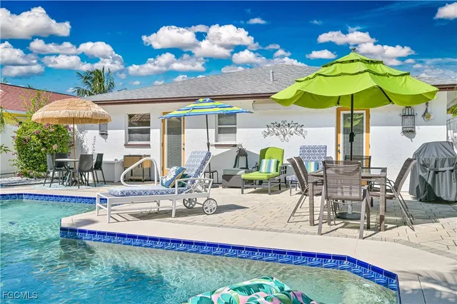 a view of a house with swimming pool lawn chairs and a yard