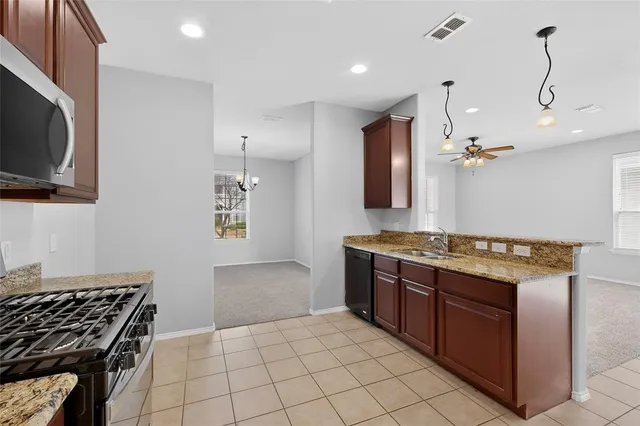a kitchen with stainless steel appliances granite countertop a stove top oven a sink and dishwasher