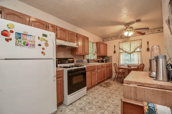 a kitchen with a refrigerator a stove a sink a dining table and chairs