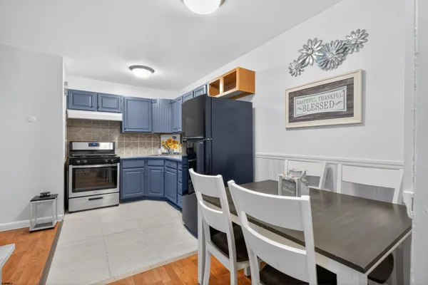 a kitchen with stainless steel appliances granite countertop a stove top oven a sink a dining table and chairs