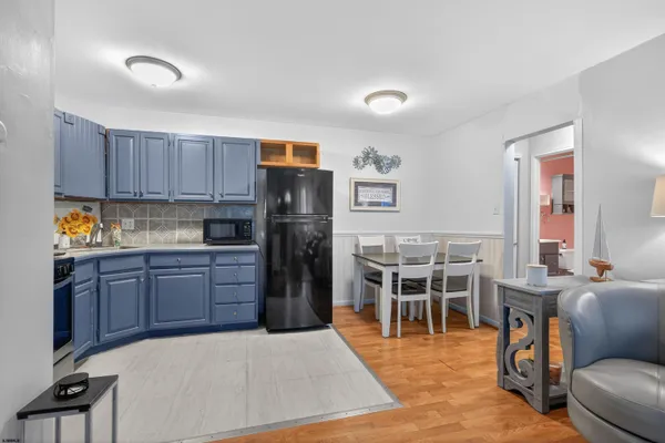 a kitchen with stainless steel appliances kitchen island granite countertop a refrigerator a stove a sink a dining table and chairs with wooden floor