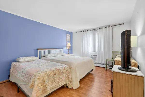 a bedroom with a bed table and a flat screen tv
