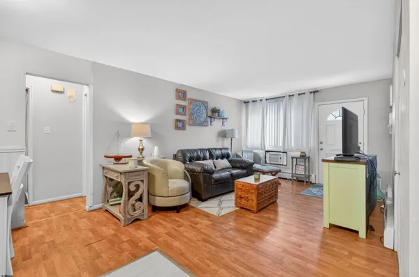 a living room with furniture a flat screen tv and a refrigerator