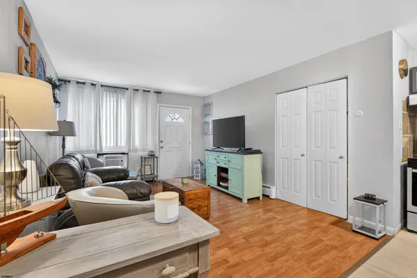 a living room with furniture a flat screen tv and a refrigerator