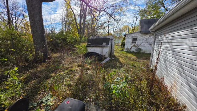 a backyard of a house with table and chairs and wooden fence