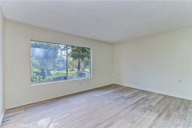 a view of an empty room with wooden floor and closet
