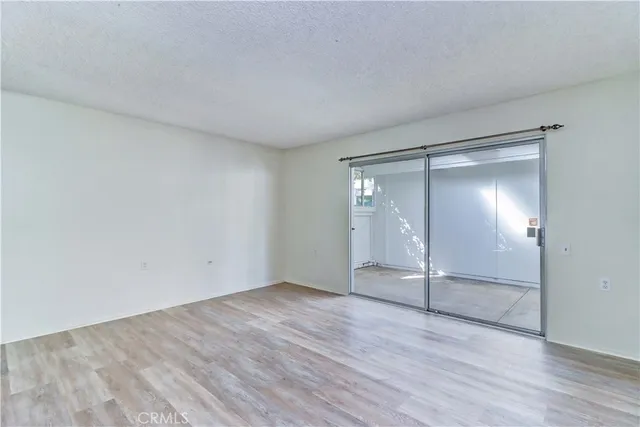 a view of an empty room with wooden floor and closet