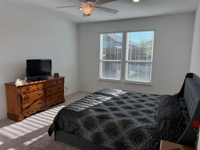 a bedroom with a bed and flat tv screen on a dresser