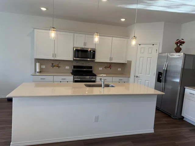 a large kitchen with stainless steel appliances a refrigerator a stove a sink a center island a stove and cabinets