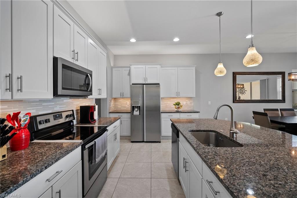 11404 Arezzo Way Fort Myers, FL 33913 - Photo 11 of 36 Kitchen with decorative backsplash, stainless steel appliances, sink, decorative light fixtures, and white cabinetry