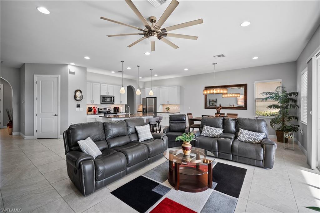 Tiled living room featuring ceiling fan with notable chandelier