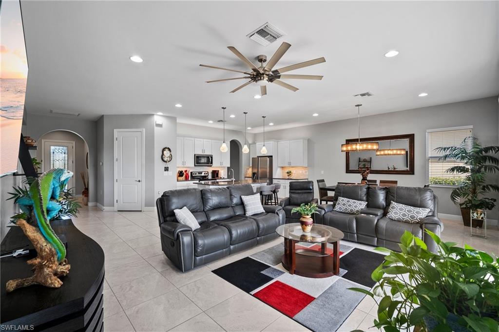 Tiled living room featuring ceiling fan with notable chandelier
