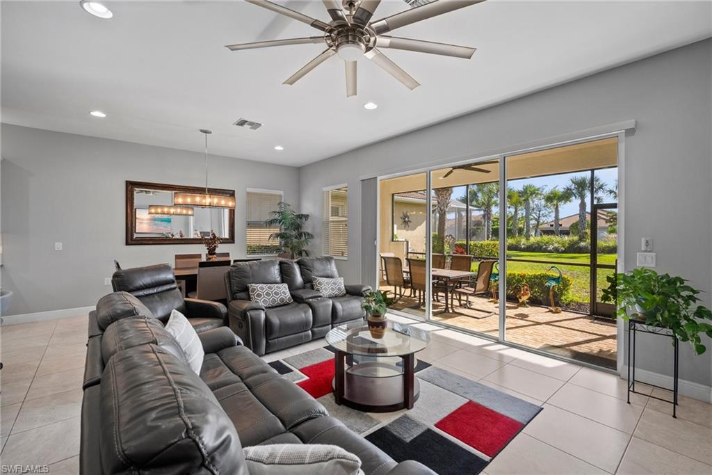 Tiled living room with ceiling fan with notable chandelier