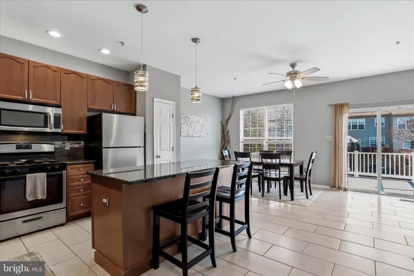 a kitchen with stainless steel appliances granite countertop a stove a refrigerator a microwave a dining table and chairs with wooden floor