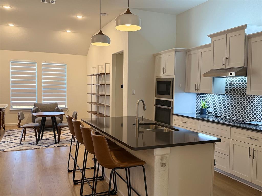 1122 Silverthorne Trail Justin, TX 76247 - Photo 3 of 19 Kitchen featuring backsplash, light wood-style flooring, hanging light fixtures, oven, and recessed lighting