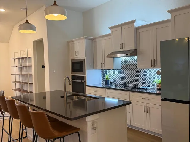 a kitchen with kitchen island granite countertop a sink a center island and cabinets
