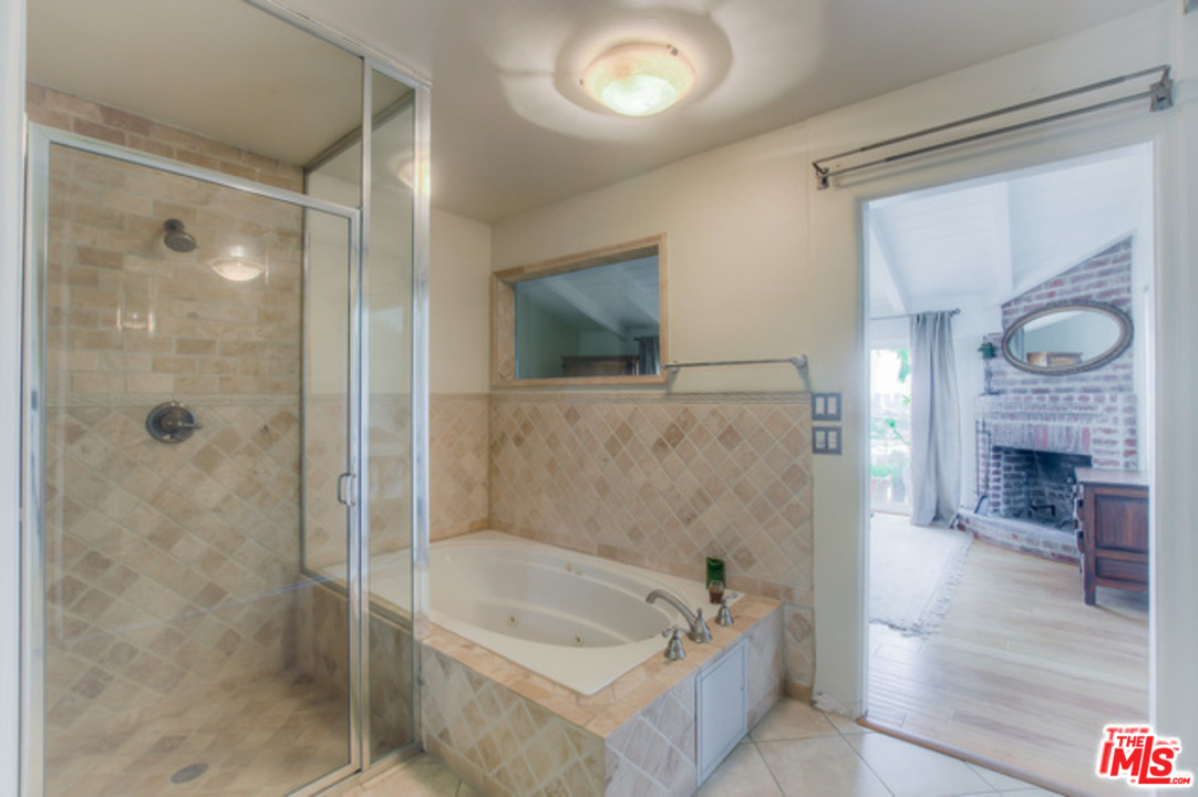 397 Fordyce Road Los Angeles, CA 90049 - Photo 8 of 9 a bathroom with a bathtub a shower a sink and a fireplace
