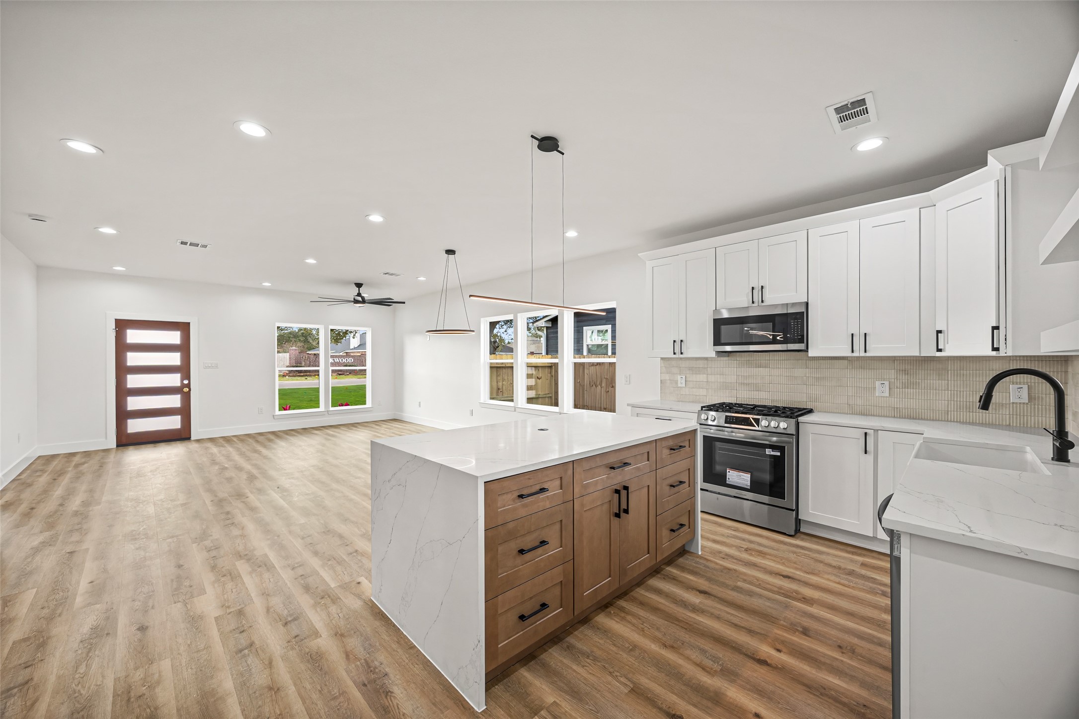 1807 Waco Street Dayton, TX 77535 - Photo 6 of 26 Oversized quartz waterfall island with natural wood cabinetry and sleek black hardware—perfect for entertaining.