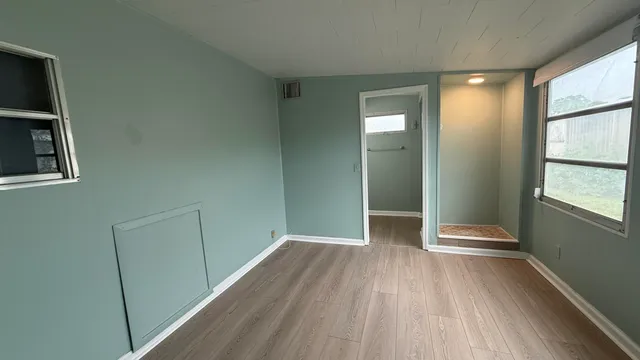 a view of an empty room with wooden floor and a window