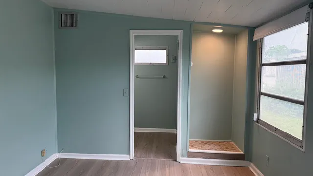 an empty room with wooden floor and windows