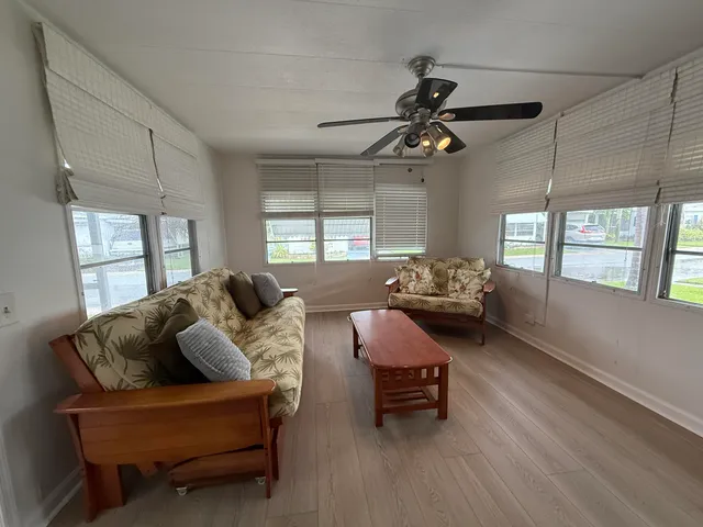 a living room with furniture two window and wooden floor