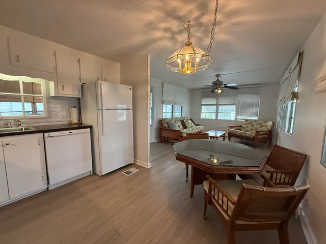 a kitchen with stainless steel appliances granite countertop a refrigerator a sink dishwasher a dining table and chairs with wooden floor