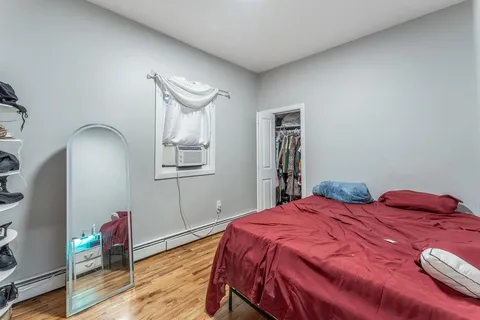 a bedroom with a bed and a dresser with wooden floor