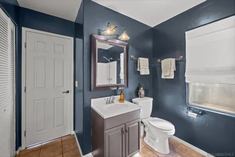 a bathroom with a toilet a sink a mirror a window and vanity