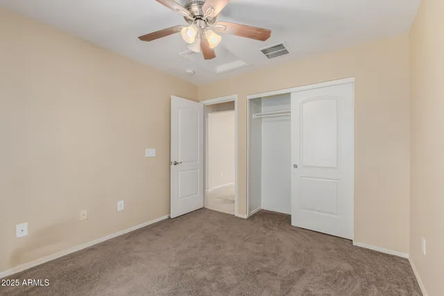 an empty room with a chandelier fan and a ceiling fan
