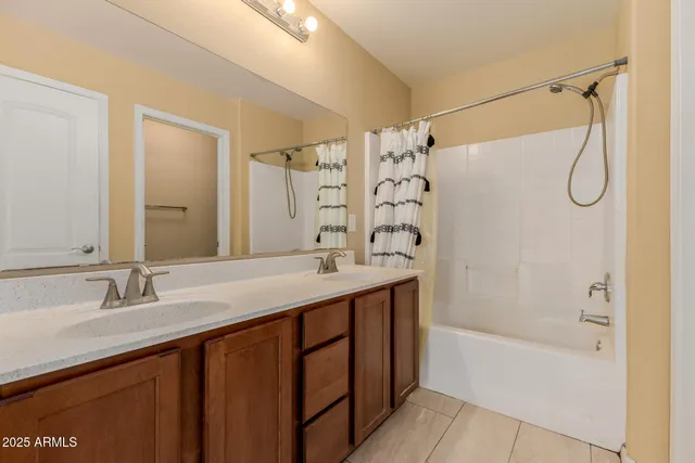 a bathroom with a double vanity sink a mirror a bathtub and shower