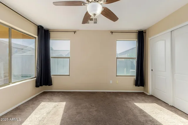 a view of a big room with windows and chandelier fan