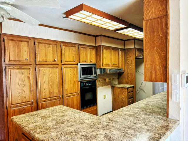 a kitchen with kitchen island granite countertop wooden cabinets a stove a sink and a refrigerator