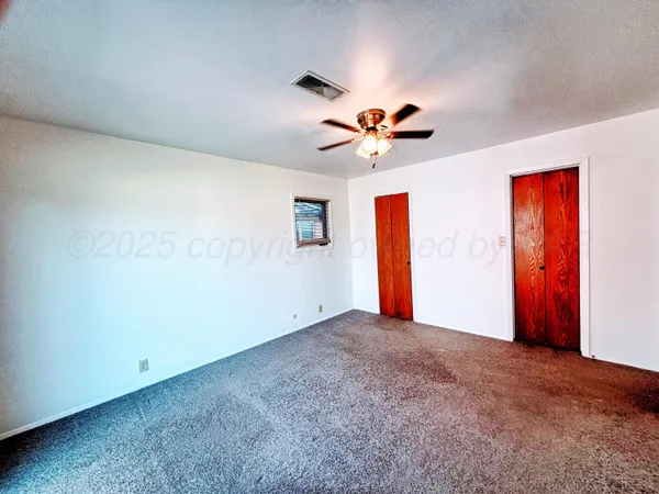an empty room with windows and fan