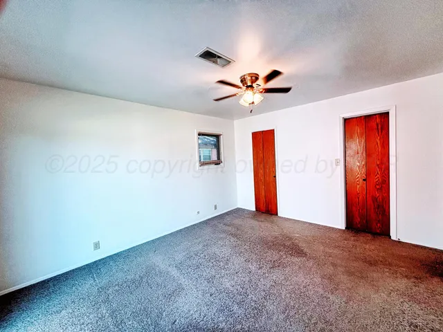 an empty room with windows and fan