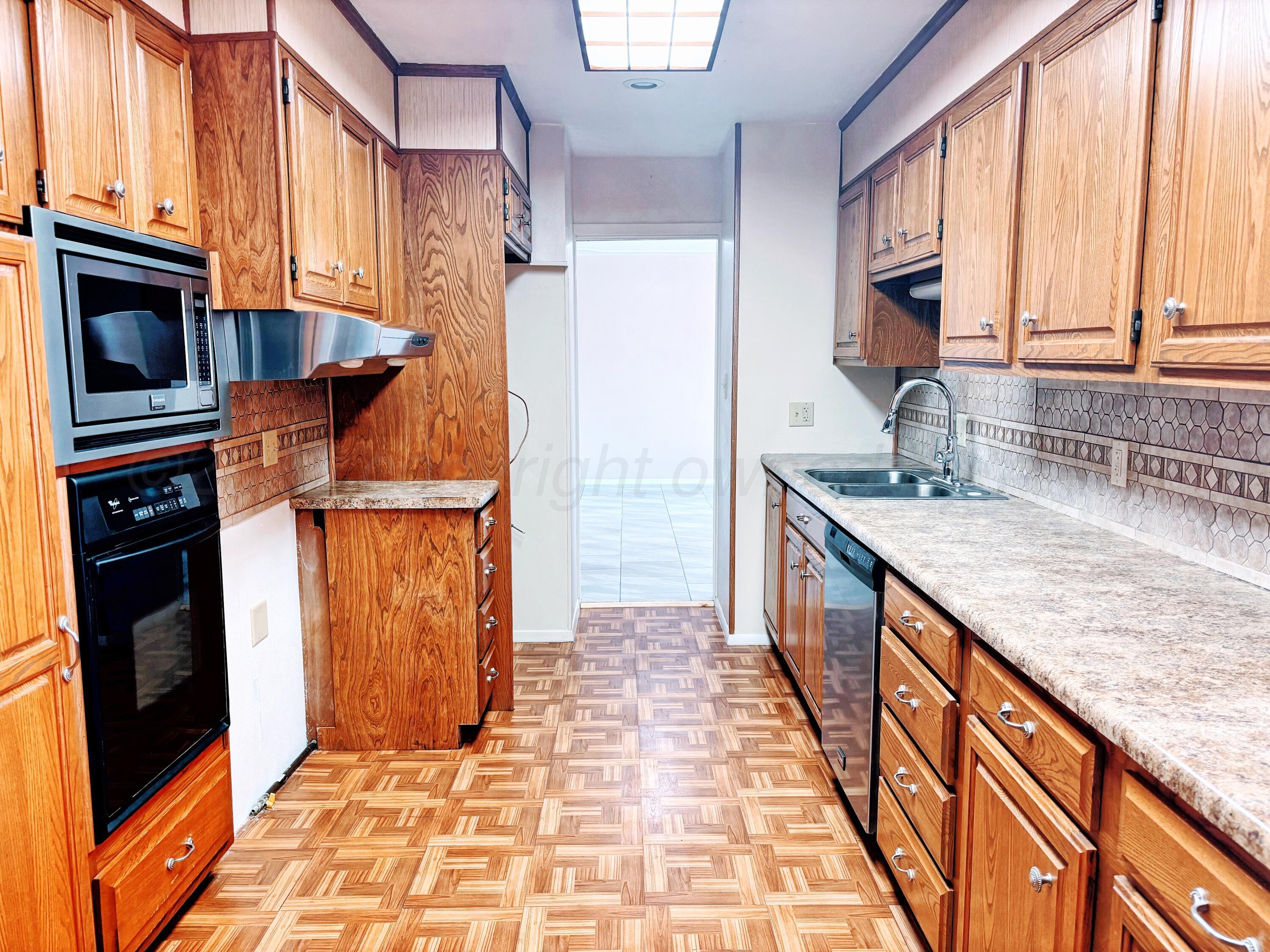 1510 South Indiana Street Perryton, TX 79070 - Photo 9 of 39 a kitchen with granite countertop a refrigerator a stove and wooden cabinets